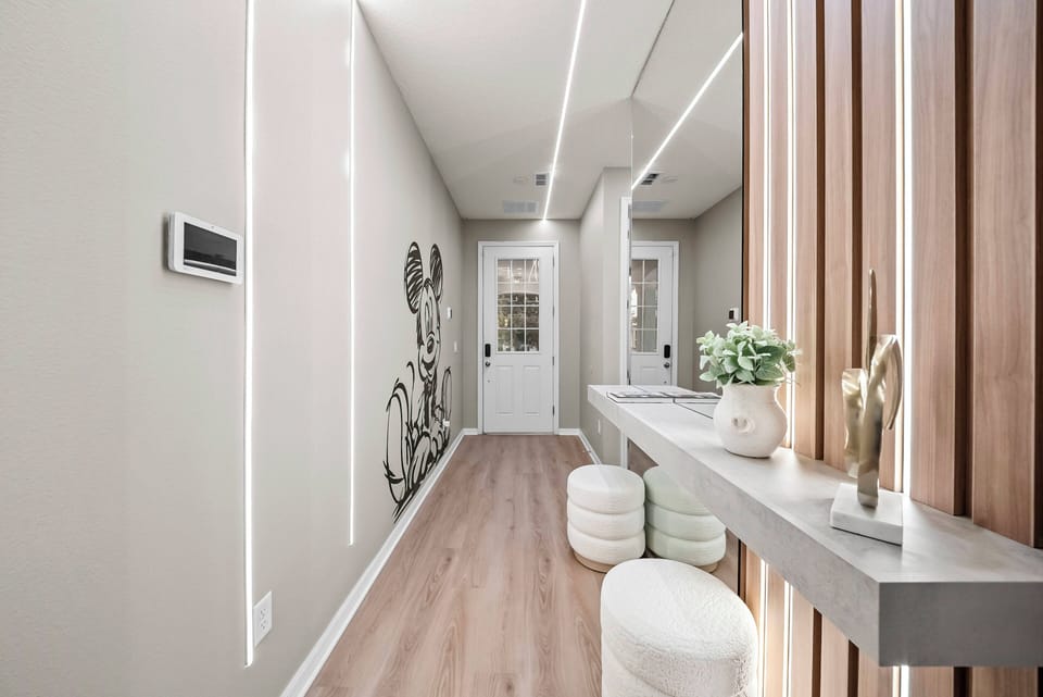 Enter a beautifully designed hallway with sleek wooden accents and modern lighting, creating a warm atmosphere. The light-toned flooring enhances the soft wall colors, making the space feel both inviting and expansive.