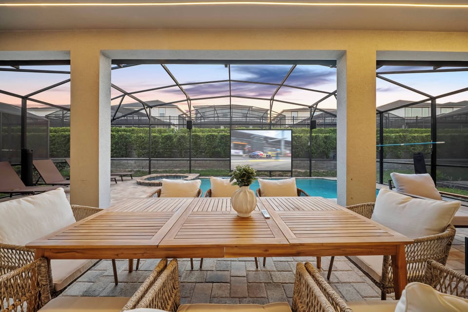 Step into this airy dining area, where a rustic wooden table invites leisurely meals against a backdrop of expansive windows. Enjoy the soothing views of the pool area framed by stylish outdoor furnishings, perfect for relaxation.