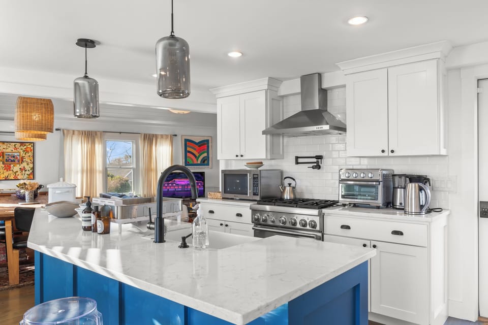Bright chef’s kitchen with blue island, pro range, subway tile & coffee bar