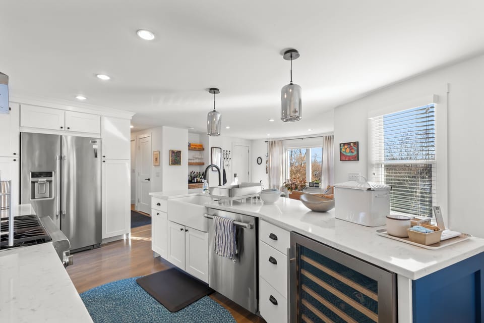 Sunlit chef’s kitchen with island, wine fridge, and open-plan flow
