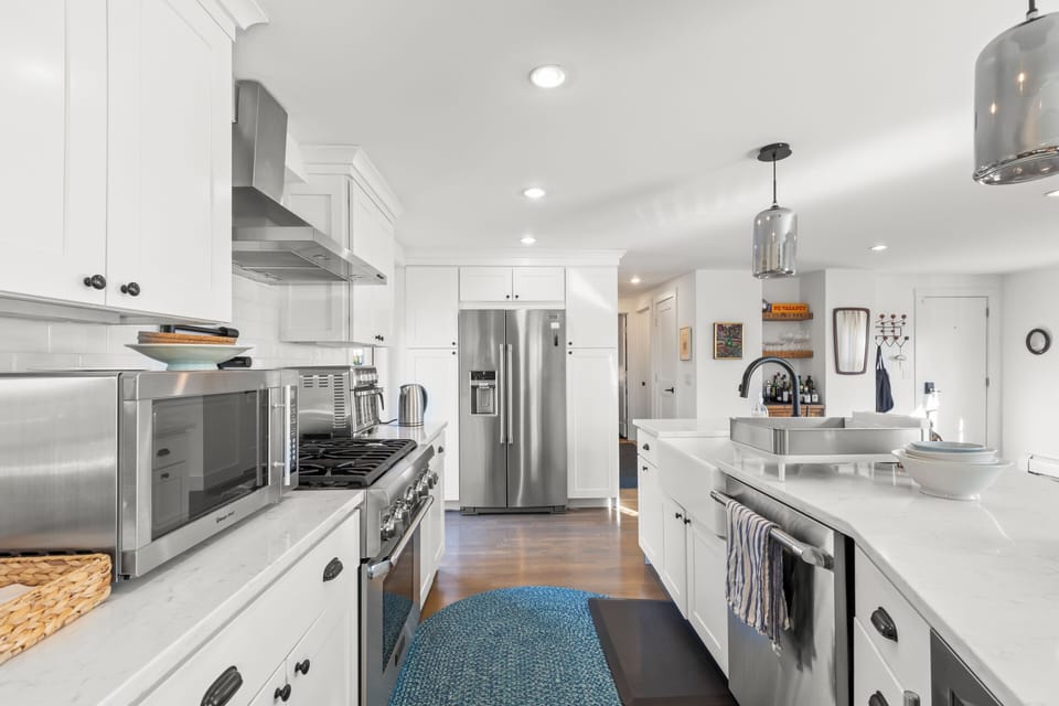 Bright chef’s kitchen with island seating, gas range, and stainless appliances.