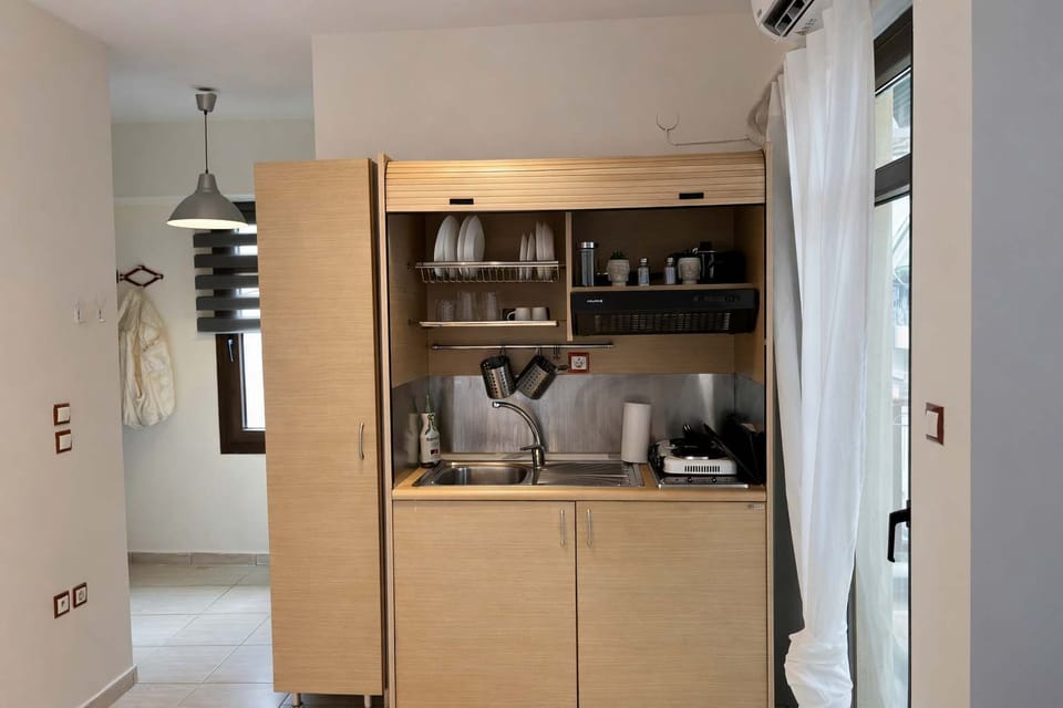 Practical studio layout with well-equipped kitchenette, wardrobe storage, shelving, and organized living space, offering comfort and convenience for both short stays and longer visits.
