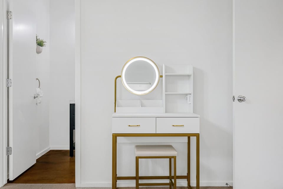 Chic vanity station with a lighted mirror, drawers, and a comfy stool.