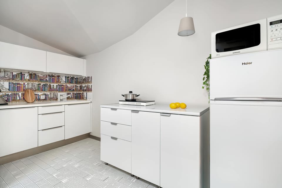 Another view of the fully equipped kitchen showing the fridge and countertop appliances. The space is bright and uncluttered, perfect for cooking.
