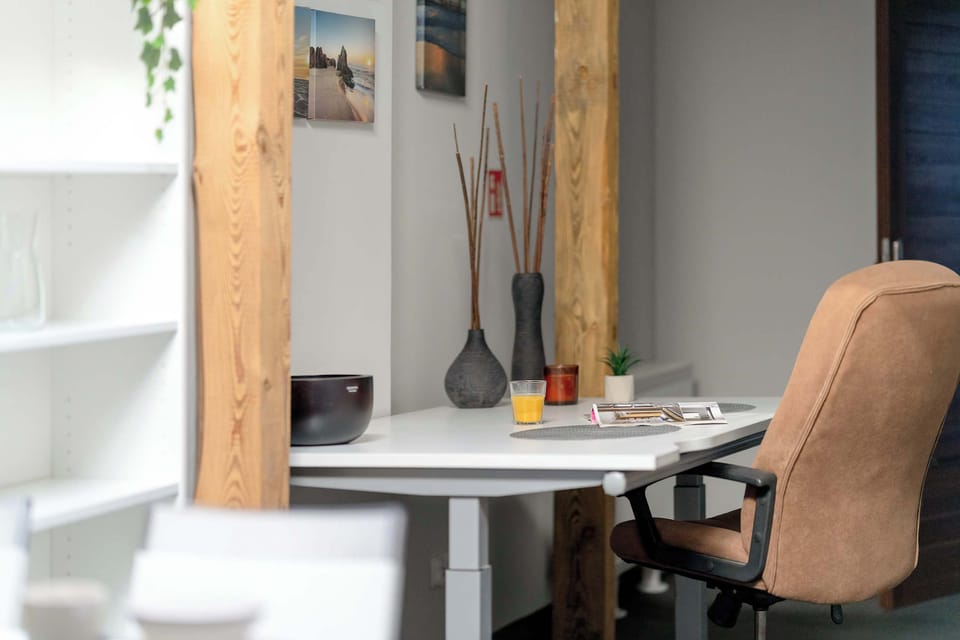 A cozy home office space with a desk and chair, adjacent to shelves for storage. Natural light makes it suitable for work or study.