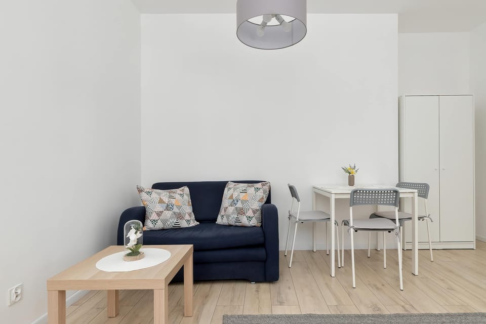 A perspective looks into the main living space, showing a blue sofa, a small coffee table, and white storage cabinet.