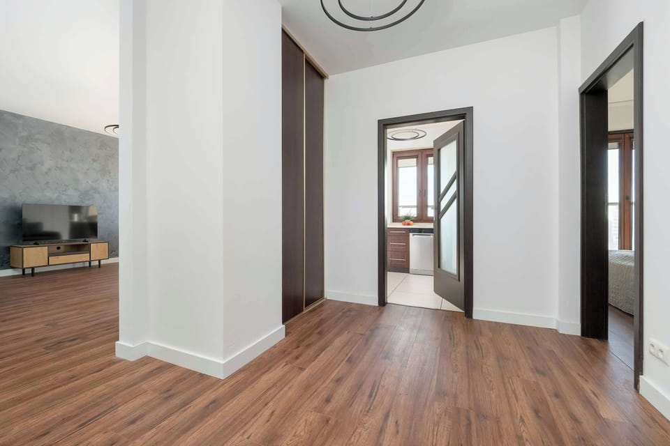 A hallway connecting the kitchen and living areas. White walls and wooden flooring create a clean and bright transition space.