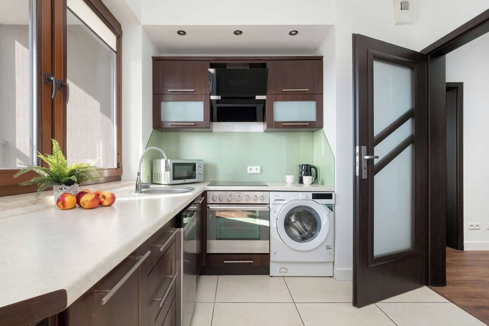 A modern kitchen with dark cabinets and light countertops. The layout provides plenty of storage and workspace for cooking.