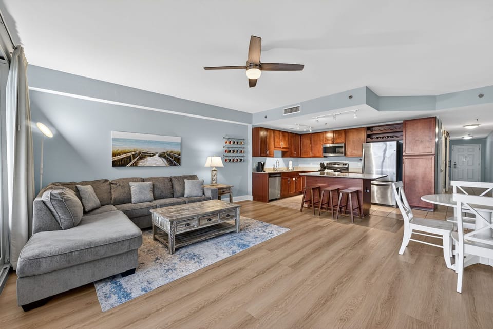 Relax in your spacious open-plan living area with comfortable seating, fully equipped kitchen, and coastal vibes throughout.
