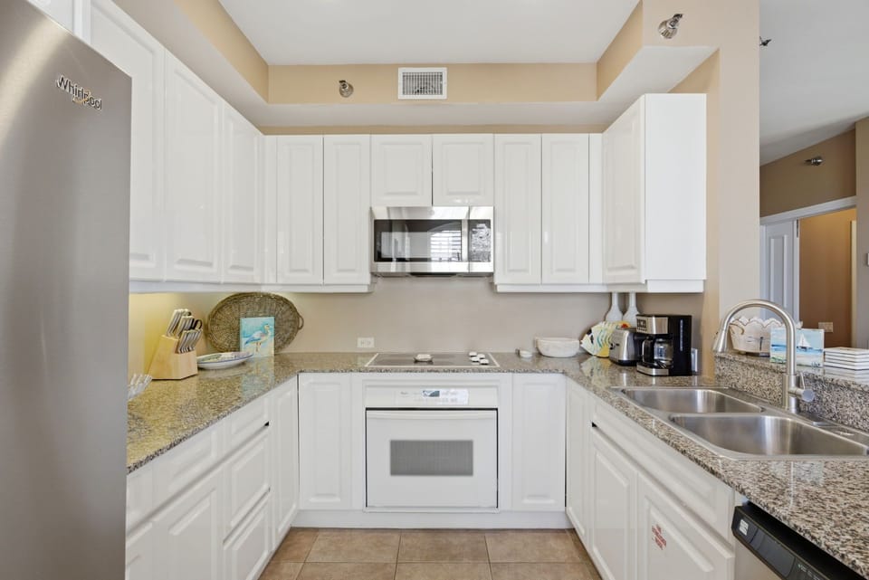 Beach Colony T PH1D- Step into your fully equipped kitchen with modern appliances, spacious granite counters, and sleek white cabinetry—perfect for preparing meals during your stay.
