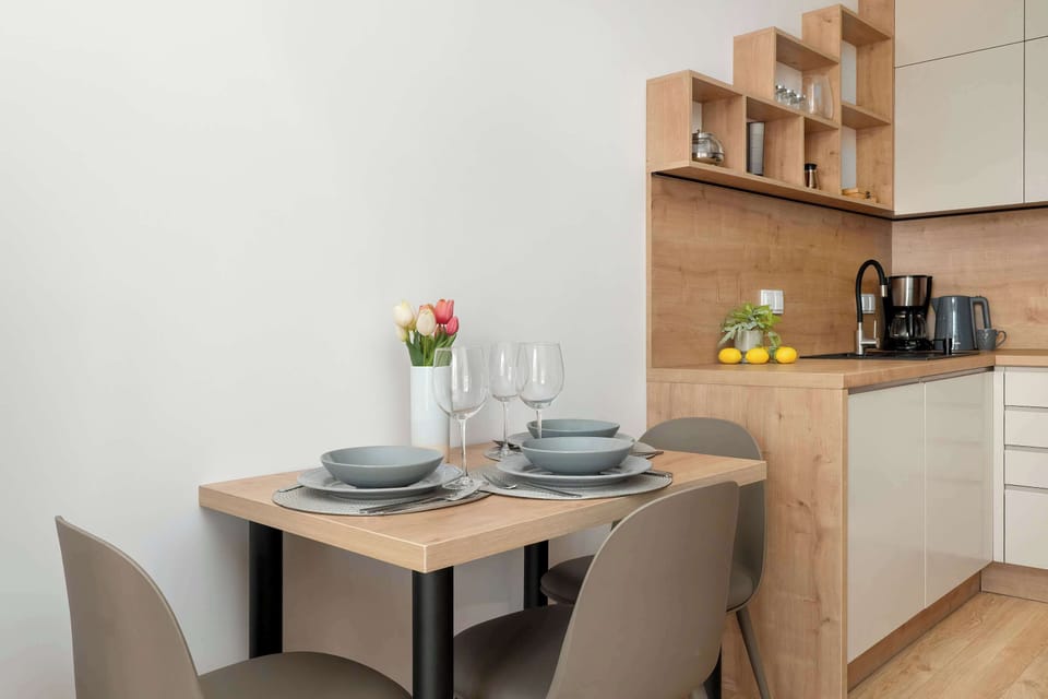 A close-up of the dining set shows a neatly set table with plates and glassware, ready for a meal. The wooden finishes in the background add warmth to the contemporary dining space.