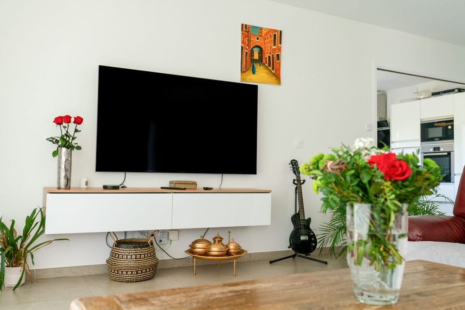 Séjour TV avec déco artistique – TV écran plat, Netflix, roses fraîches et ambiance musicale pour des soirées de charme