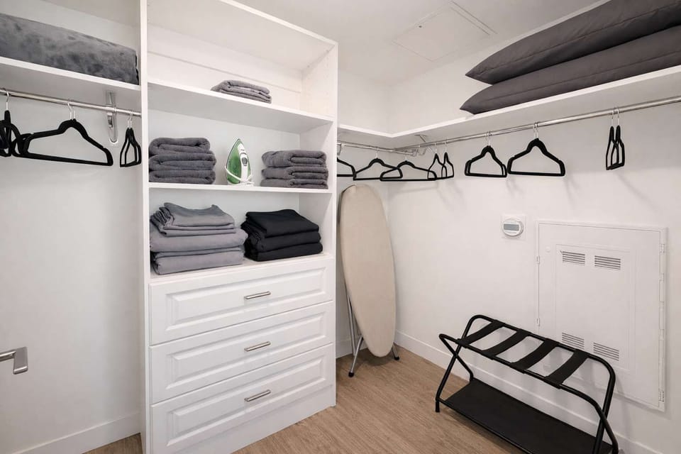 A spacious walk-in closet stocked with extra sheets, pillows, blankets, an iron, an ironing board, and a crib for your convenience