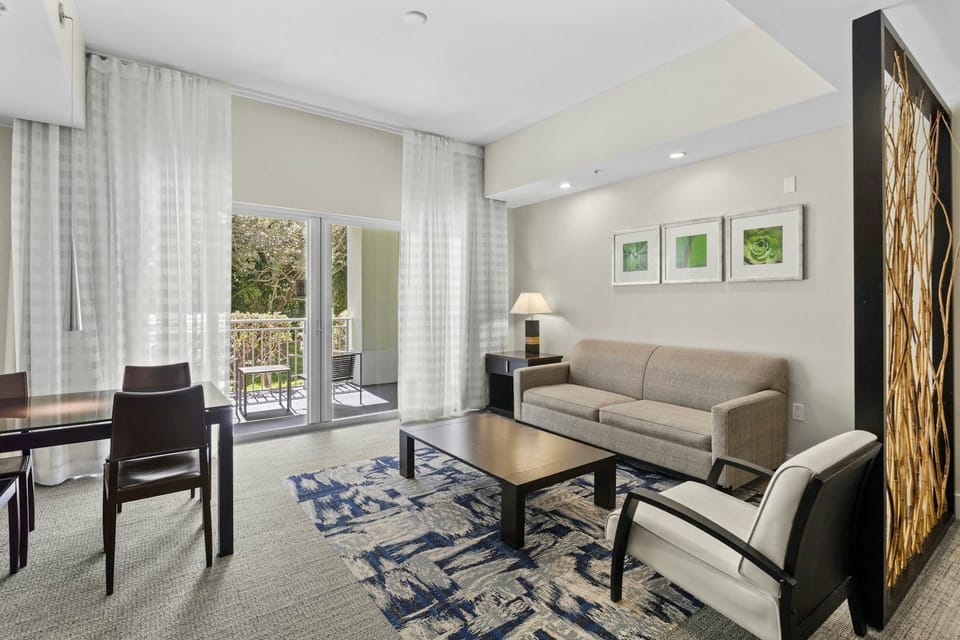 Bright living and dining area with modern furnishings, an open layout, and natural light from the balcony doors.