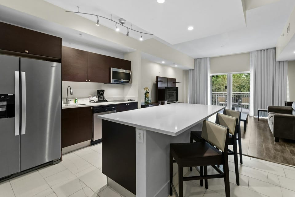 Sunlit kitchen showcasing moderm cabinetry, granite countertop, and modern appliances.