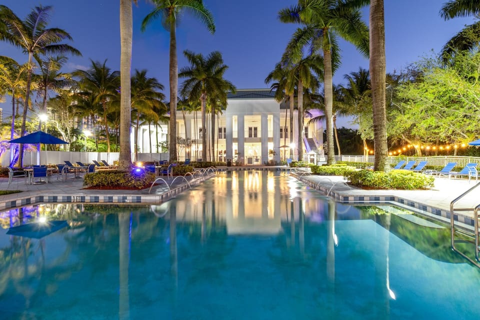 Relax in a stunning palm-lined resort pool, beautifully illuminated at night for a true tropical escape.