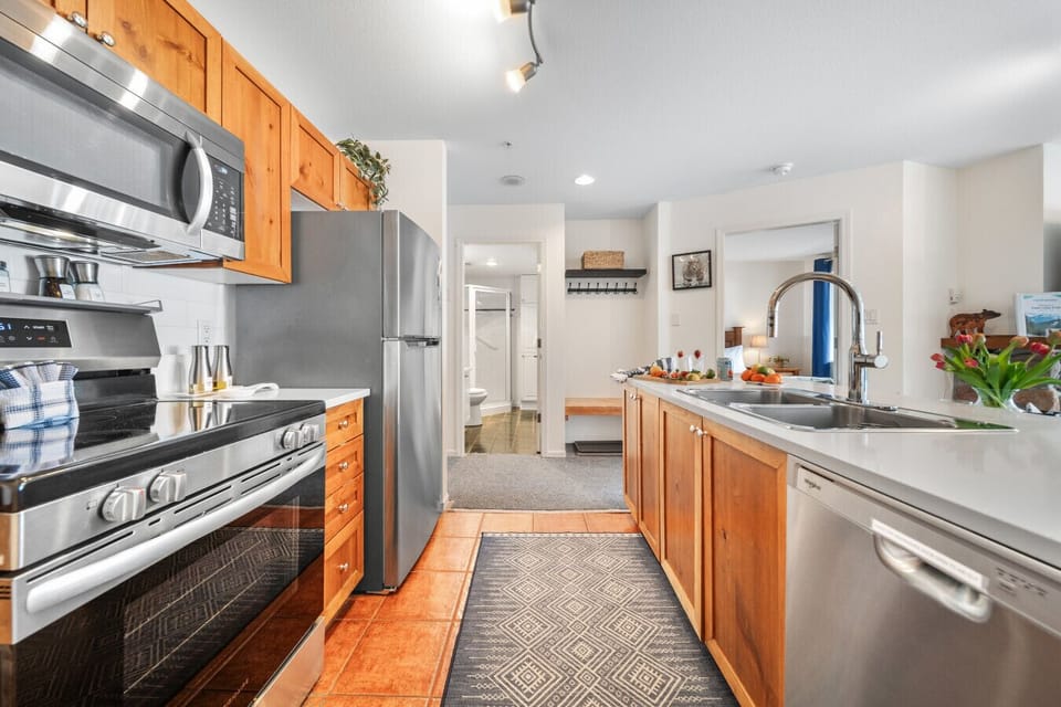 Fully stocked kitchen with stainless steel appliances, full-size fridge, stove, microwave, dishwasher, plus a convenient mudroom bench and coat hooks for extra storage and comfort.