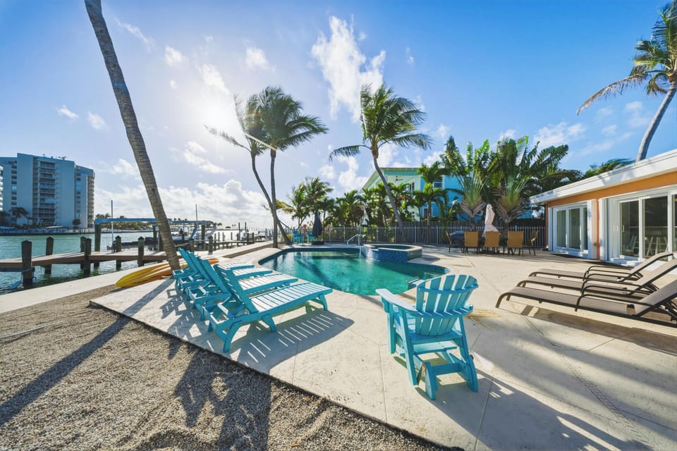Resort-style pool and hot tub in a Marathon FL vacation rental with comfortable loungers and canal views.