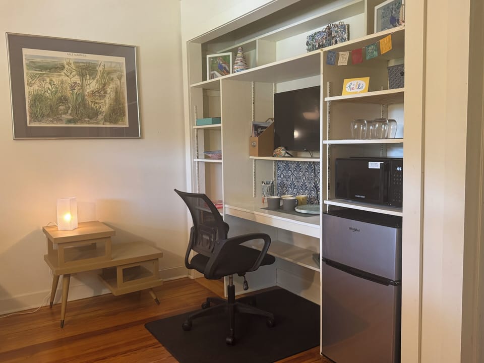 Flex space with desk, kitchenette appliances, and TV in second BR