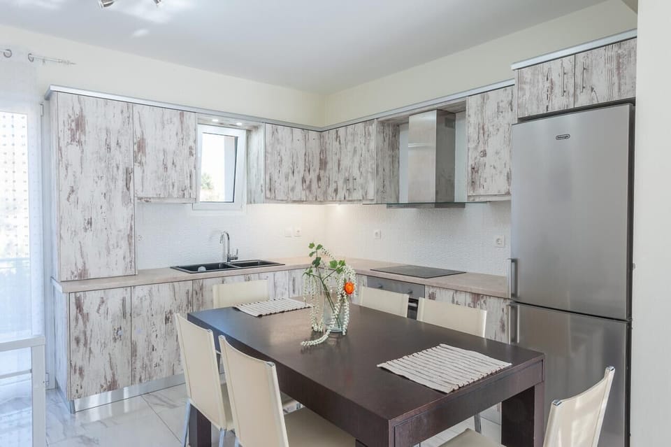 Modern kitchen with marble-style finishes and dining table.