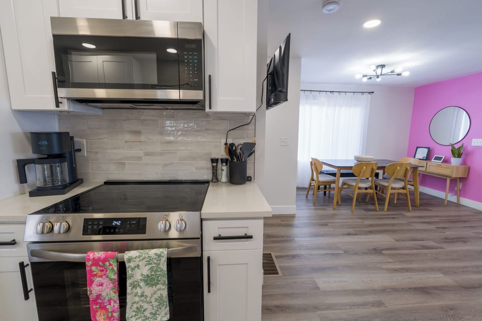 Your modern kitchen features stainless appliances and flows into a bright dining space with cheerful pink accent wall.