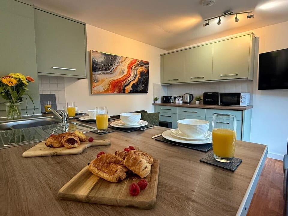 The kitchen and breakfast bar set with plates and orange juice, showing how the dining and cooking areas flow together.