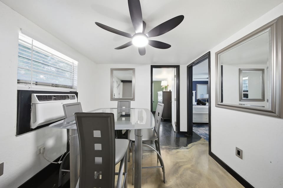 Bright modern dining nook with glass table, A/C, and stylish mirrors