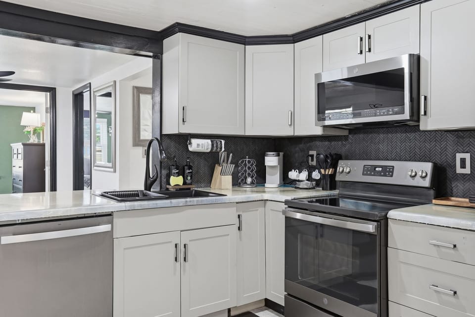 Modern kitchen with stainless appliances and stylish black backsplash