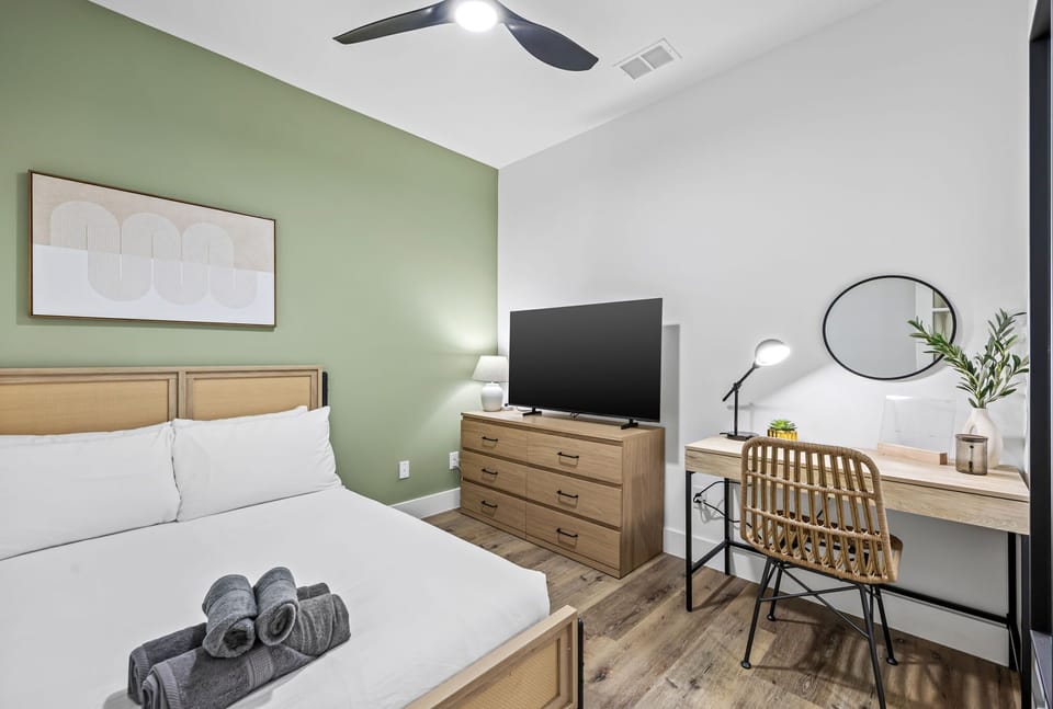 Green serenity: A chic full suite featuring a dedicated work nook and a large Smart TV for the perfect blend of productivity and relaxation.