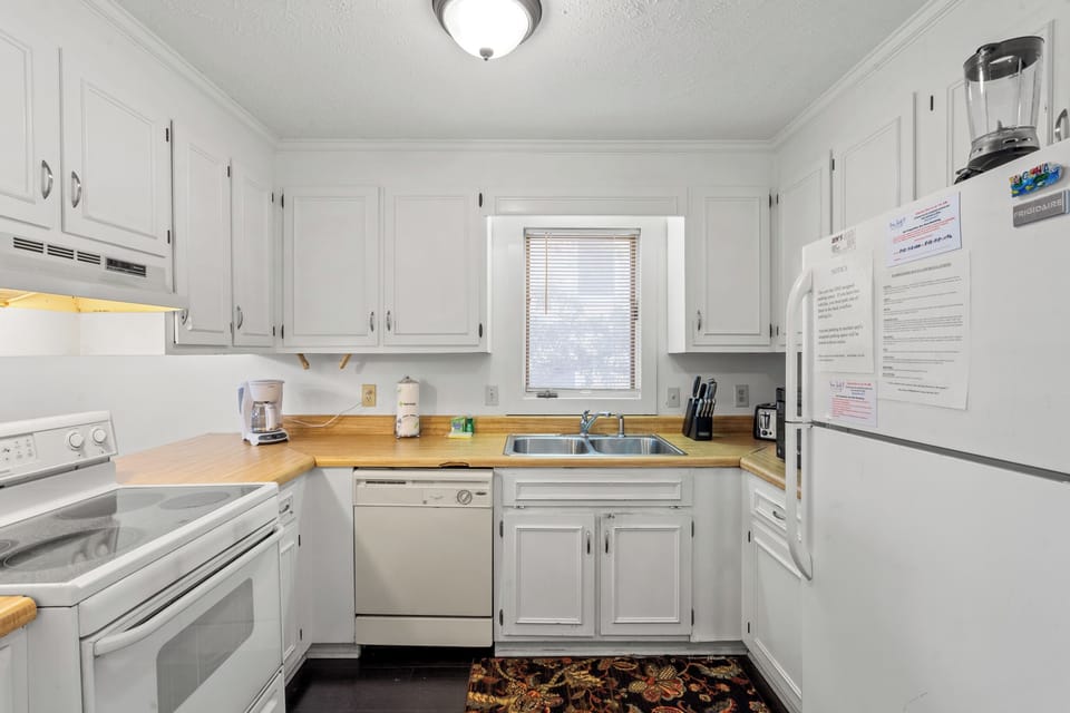Cook your favorite meals in this fully equipped kitchen with white cabinets, wood countertops, and all the appliances you need for a comfortable stay.