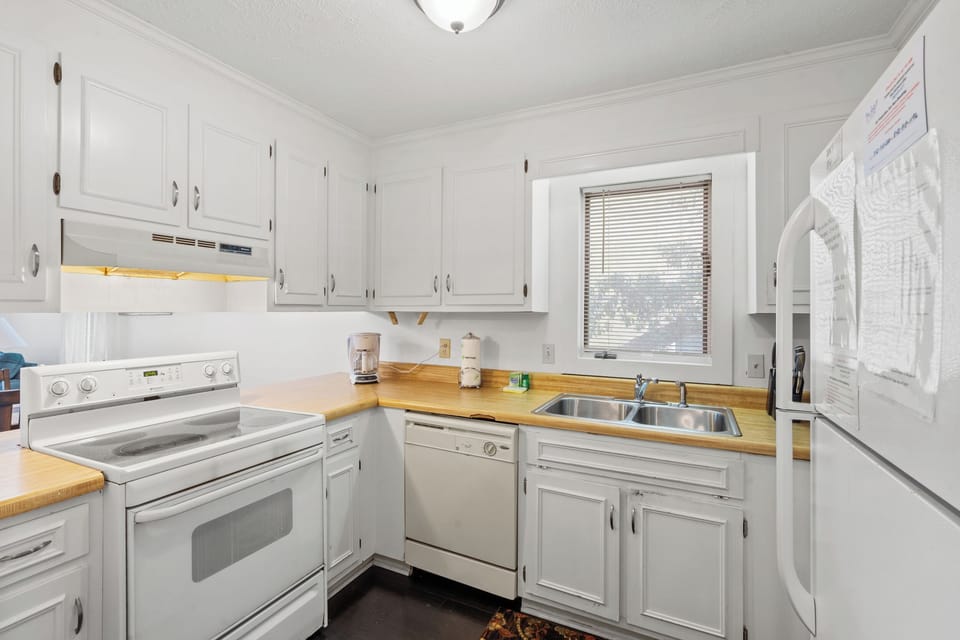 Your fully equipped kitchen awaits with warm wood counters, crisp white cabinets, and everything needed to create memorable meals during your stay.
