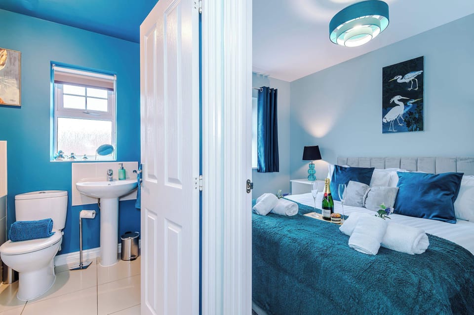 Enjoy a modern bedroom with teal details, fresh linens, and a romantic setup. Rolled towels and wine add charm, complemented by a bright en‑suite bathroom for a complete guest retreat.