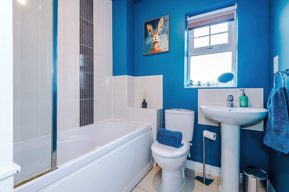 Enjoy a well‑appointed bathroom featuring a bathtub with shower screen, pedestal sink, and thoughtful details. Blue accents and natural light make this space both practical and relaxing.
