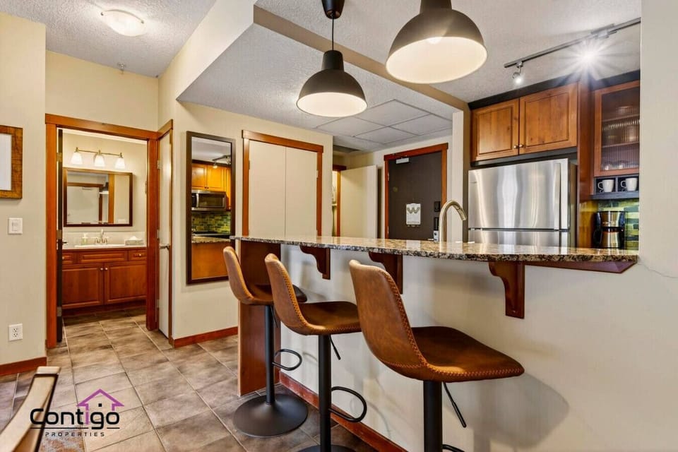 Modern kitchen featuring stainless steel appliances and bar seating, providing the perfect setup for home-cooked family meals in Canmore.