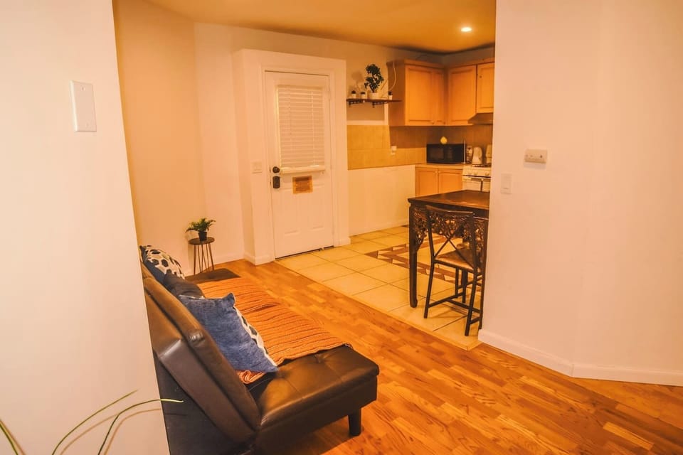 Perspective connecting the living room to the kitchen, featuring the main entrance and a high table perfect for dining or working.
