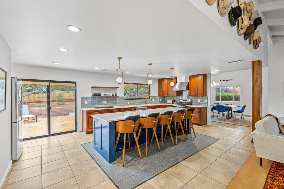 Bright kitchen featuring a large island, bar stools, and sliding doors leading to the outdoor patio.