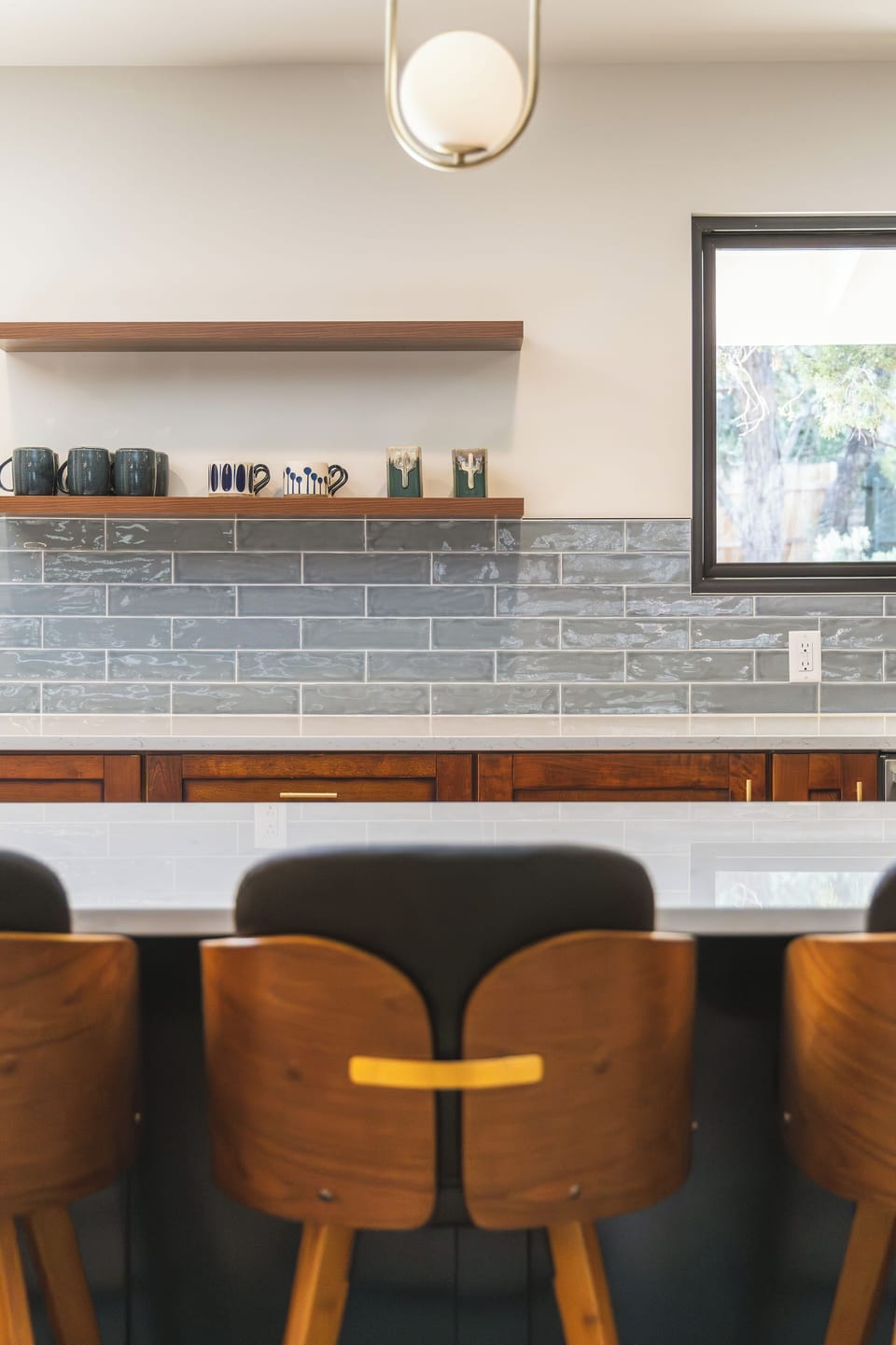 Modern kitchen counter with bar seating and a sleek tile backsplash.