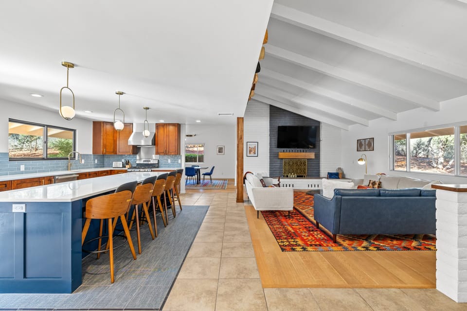 Bright open living space connecting the kitchen, dining area, and cozy living room with fireplace.
