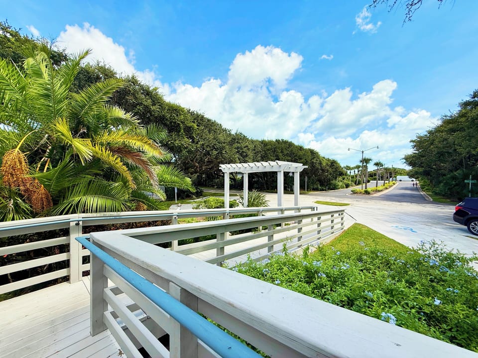 Start your beach stay with this inviting boardwalk entrance surrounded by lush palms and coastal greenery. Just moments from the sand, this scenic setting welcomes you to relax and enjoy your seaside vacation rental.