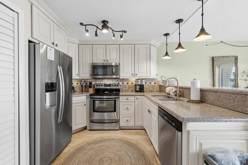 Prepare meals with ease in this updated coastal kitchen featuring stainless steel appliances, spacious counters, and an open layout. Perfect for a comfortable beach stay after a day of sun, sand, and ocean adventures.