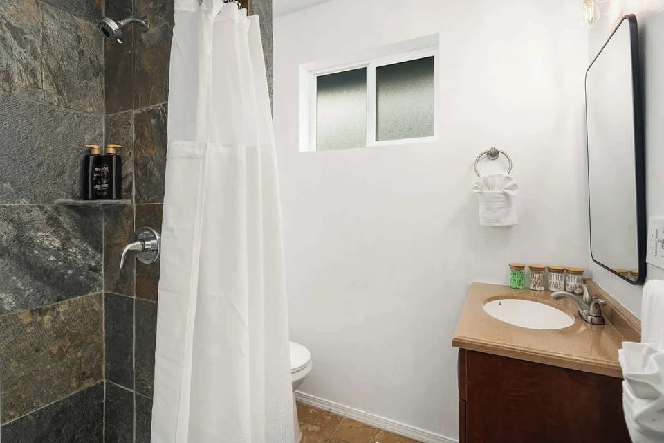 Relax in this sleek, modern bathroom featuring a natural stone shower and a bright, airy design.