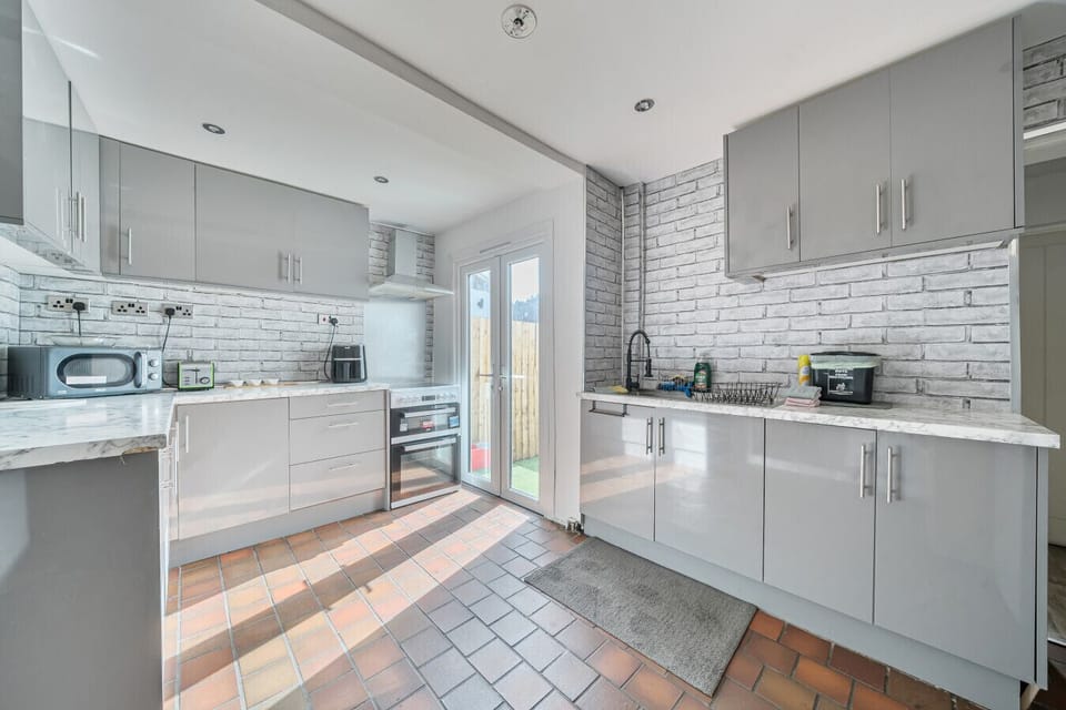 Fully equipped kitchen with gloss grey units, double oven, and direct access to the garden so cooking feels effortless.