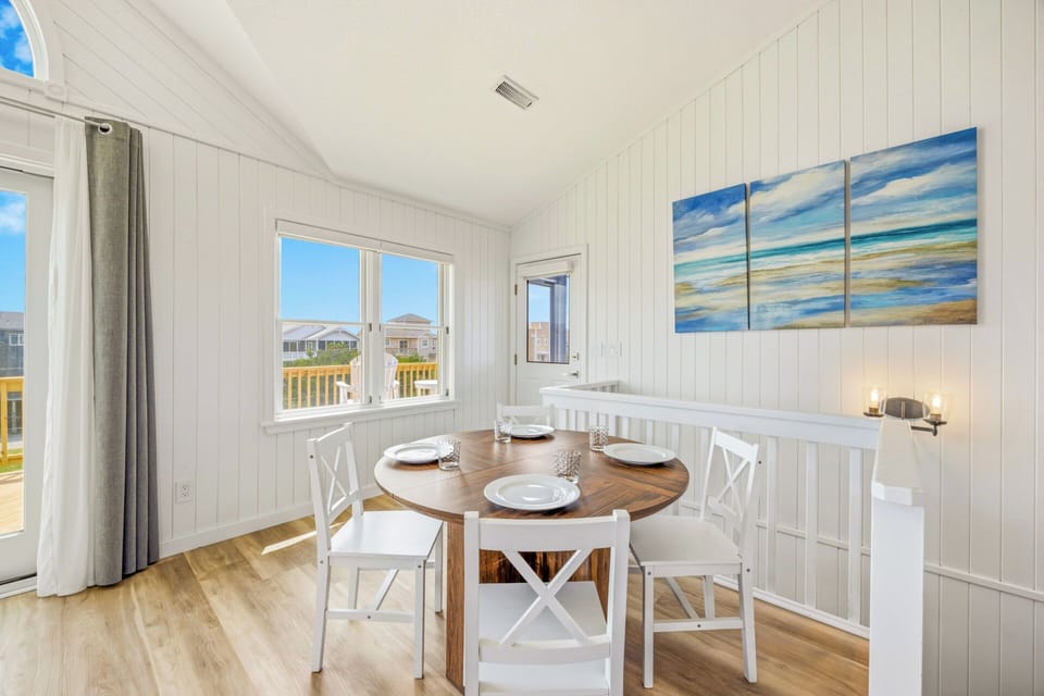 Gather around this charming dining nook where warm wood meets coastal elegance. Natural light pours through large windows, inviting you to linger over meals with loved ones in your beach retreat.