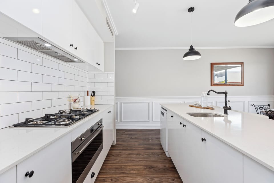 Enjoy a seamless cooking experience in this bright, modern kitchen, featuring high-end appliances, crisp subway tiling, and a spacious island that's perfect for meal prep.