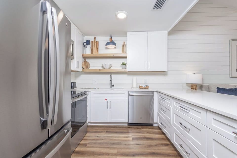 Kitchen - The beautiful kitchen features stainless appliances which include a dishwasher, stove, built-in microwave, and refrigerator. Each cabinet and drawer is fully stocked with meal prepping items.