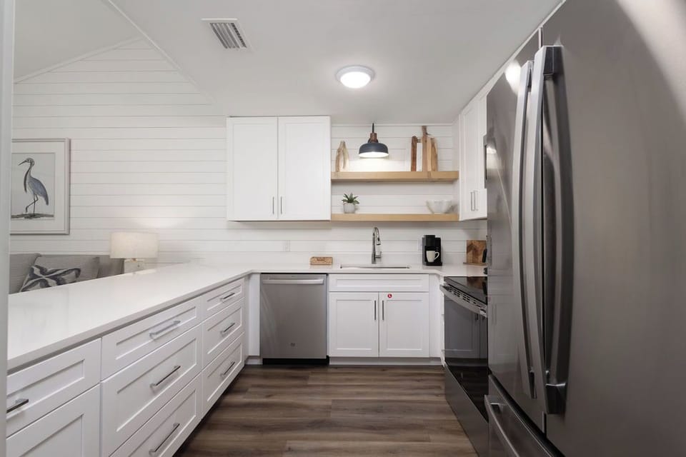 Kitchen - The beautiful kitchen features stainless appliances which include a dishwasher, stove, built-in microwave, and refrigerator. Each cabinet and drawer is fully stocked with meal prepping items.