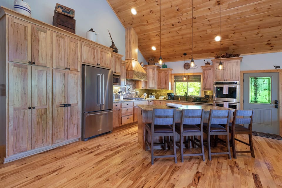 Chef's Kitchen – Stainless Appliances and Island Seating - Chef's kitchen with wood cabinetry, stainless appliances, gas cooktop, and island seating.