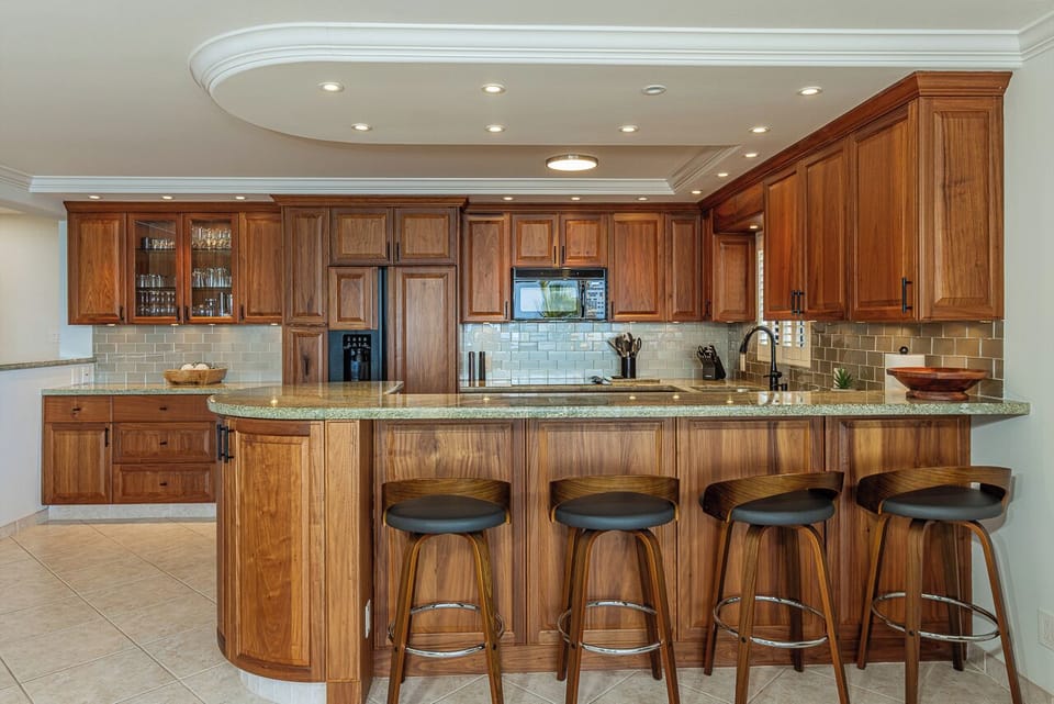 Your gourmet kitchen awaits with rich wood cabinetry, granite counters, and a curved breakfast bar perfect for morning coffee or evening conversations.