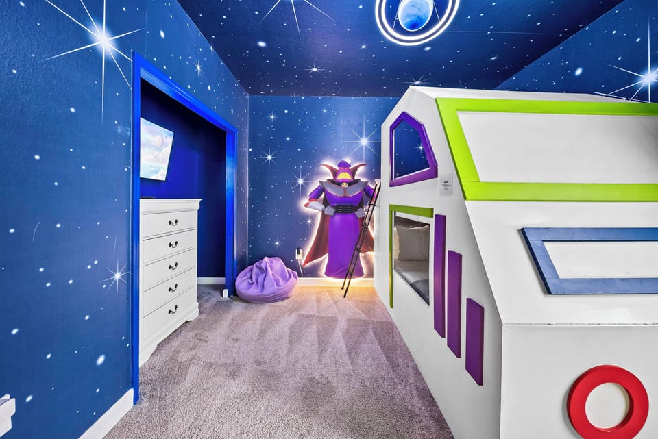 Welcome to a whimsical kids' room featuring a playful starry sky mural and vibrant blue walls. The cozy playhouse-style bunk bed sparks imagination, while the soft carpet provides comfort for little feet to explore and play.