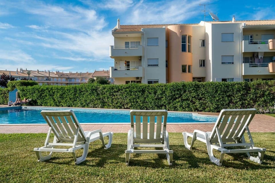 Piscina privada do condomínio - tem piscina para crianças, piscina para adultos e um um jardim grande com quatro espreguiçadeiras pertencentes ao apartamento. 